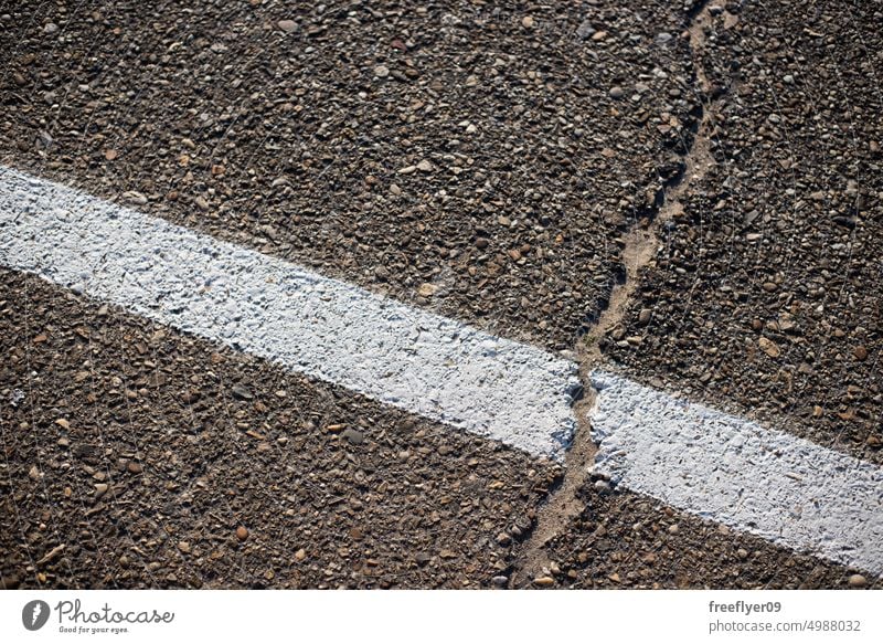 Closeup with a cracked white painted line from the hot temperatures asphalt detail roadside surface signs closeup boundary street rough texture background solid