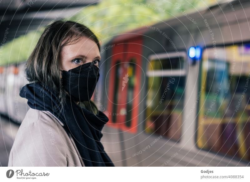 Young woman with mouth guard stands on a platform waiting for the arriving suburban train | Corona thoughts Woman Mask corona Train station Track SBahn