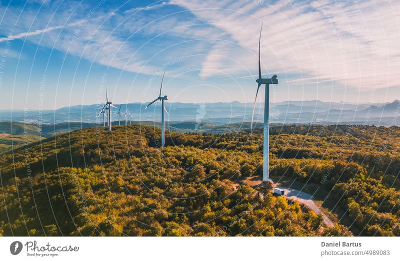View of a wind farm in a mountainous forest field with mountains in the background. View during the rising sun. Sunrise energy sky turbine windmill power nature