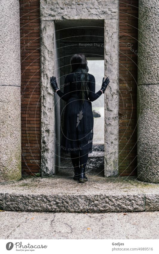 [HH Unnamed Road] Rear view of a woman dressed in black in the entrance of a memorial site. Woman commemoration Gothic style Black Grief Light Shadow