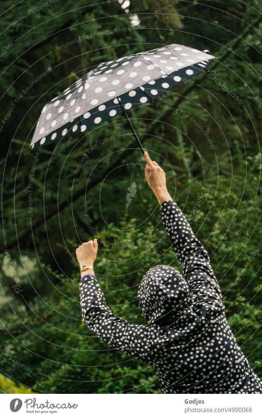 [HH Unnamed Road] rear view of person wearing dotted rain jacket and matching raised umbrella. one person Woman Outdoors Nature Umbrella Spotted Green