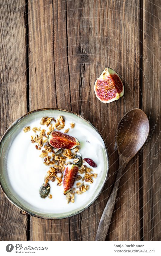 A bowl of yogurt, crunchy cereal and figs on a wooden table. Top view. Breakfast Cereal Yoghurt Fig Rustic superfood Diet Healthy Spoon Wooden table Oat flakes