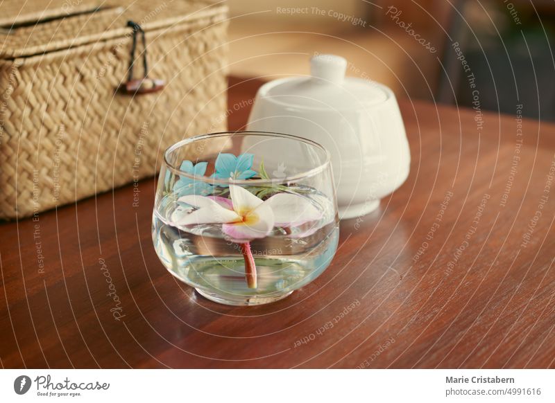 A frangipani flower in a glass of water as a table centerpiece showing a relaxing living space, wellness and wellbeing Detox Centerpiece Table Wellbeing