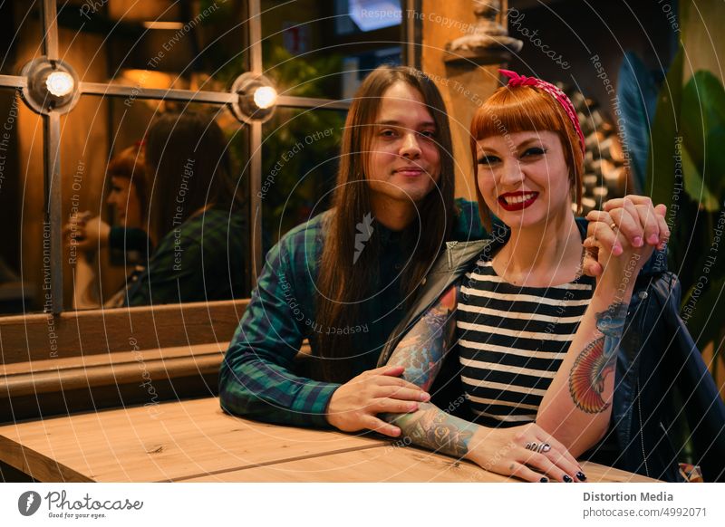Smiling couple in a coffee shop looking at camera. She is red-haired and has a pin-up style adult beautiful bonding boyfriend celebration cheerful club