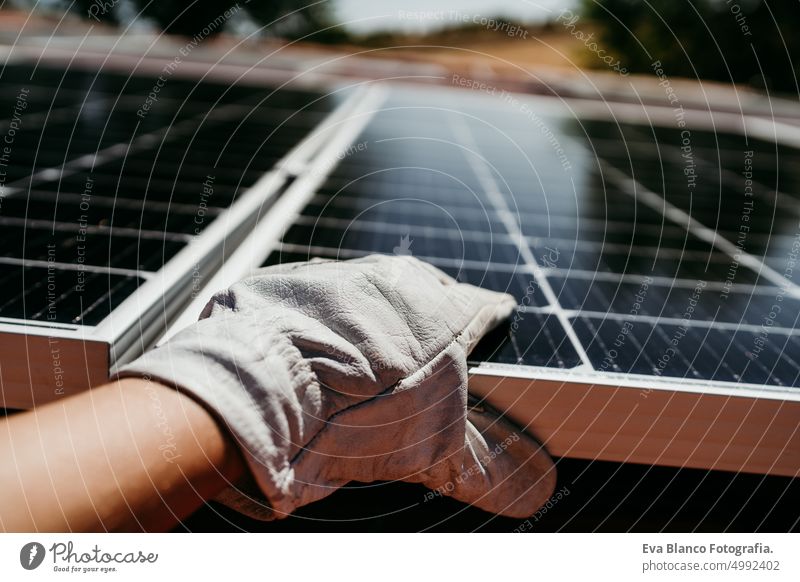 close up of hand of mature Technician man touching solar panels on house roof for self consumption energy. Renewable energies and green energy concept drill