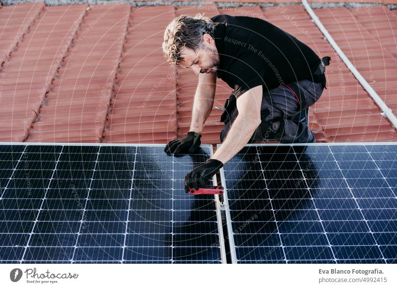 mature Technician man assembling solar panels on house roof for self consumption energy. Renewable energies concept green energy technician photovoltaic tools