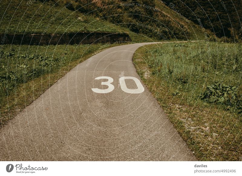 Bike lane crossing the countryside with 30 number painted in white on the tarmac. alley alps asphalt bicycle bicycle lane bicycle path bike bike lane floor