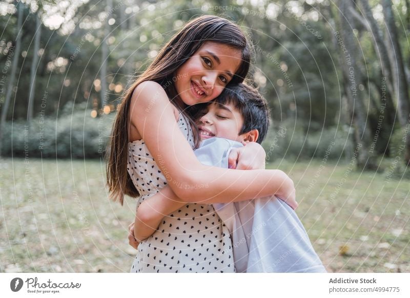 Smiling sister embracing brother on meadow in afternoon embrace love smile sincere eyes closed childhood portrait girl boy cheerful dreamy sibling together