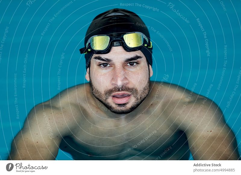 Swimmer in goggles leaning on poolside swimmer lean on hand masculine man portrait athlete sport macho tired accessory sportsman glad swimming modern