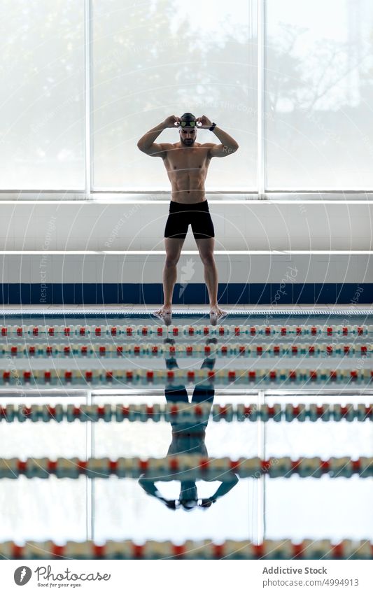 Swimmer with goggles reflecting in pool indoors athlete swimming sport strong naked torso masculine body man prepare swimmer lifesaver reflection shirtless