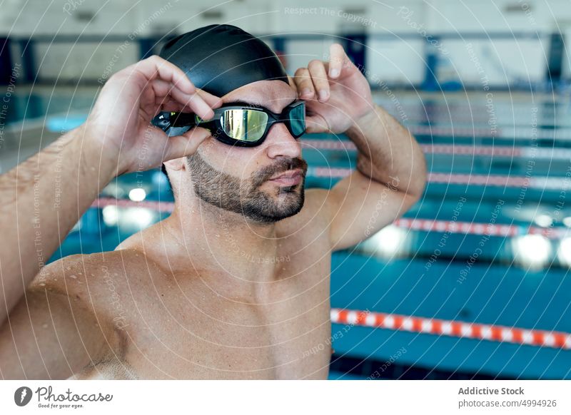 Muscular swimmer in goggles and cap against pool athlete sporty masculine macho man portrait brutal triceps shirtless muscle accessory muscular sportsman