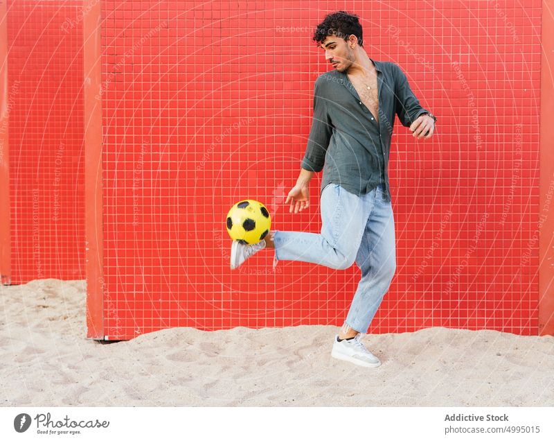 Hispanic male doing trick with football ball man kick street wall colorful bright activity practice weekend young hispanic ethnic juggle urban energy soccer