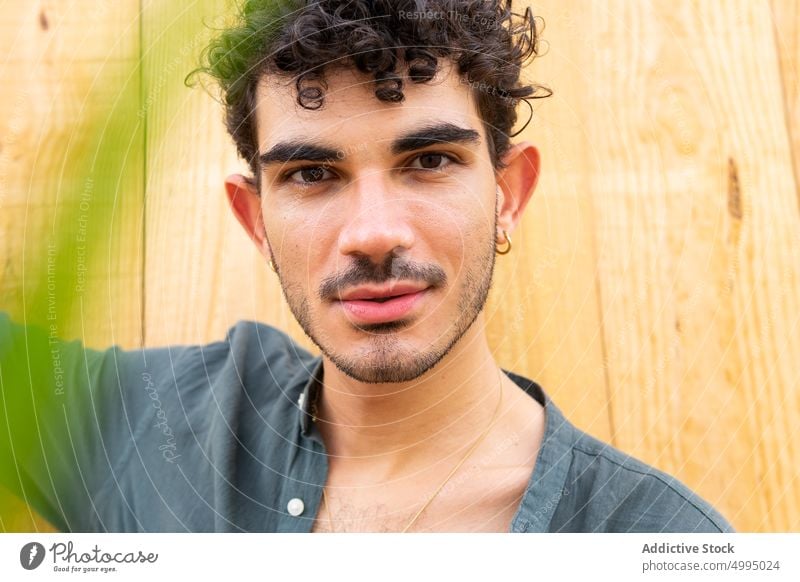 Hispanic male against wooden wall man style lean modern model curly hair portrait building young hispanic ethnic summer individuality appearance lumber timber