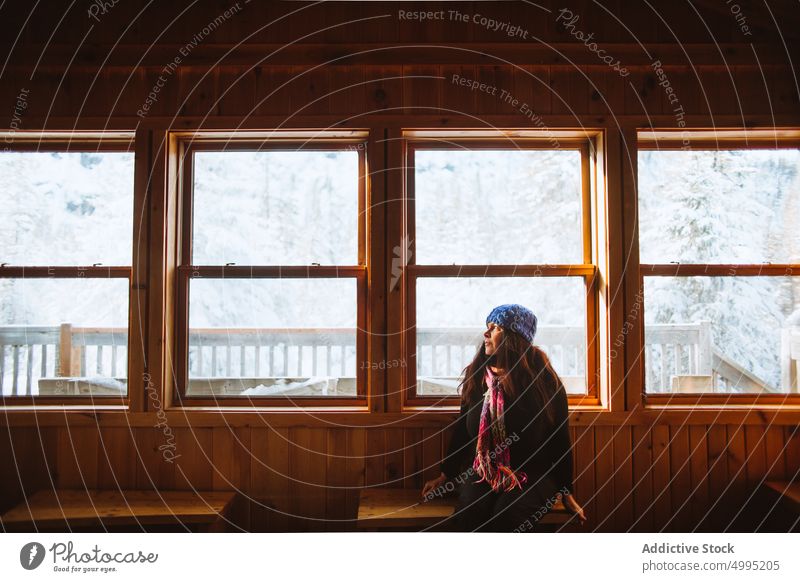 Female traveler inside wooden cabin woman hut weekend winter trip bench window visit season valley of the ghosts monts valin quebec canada national park snow