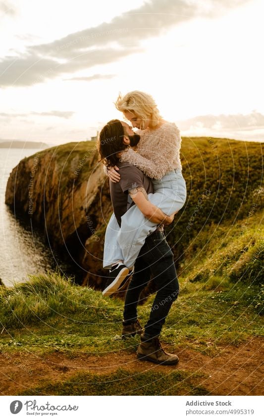 Man lifting woman on cliff near sea couple hug love sunset date romantic cloudy sky aviles asturias spain evening nature embrace boyfriend girlfriend sundown