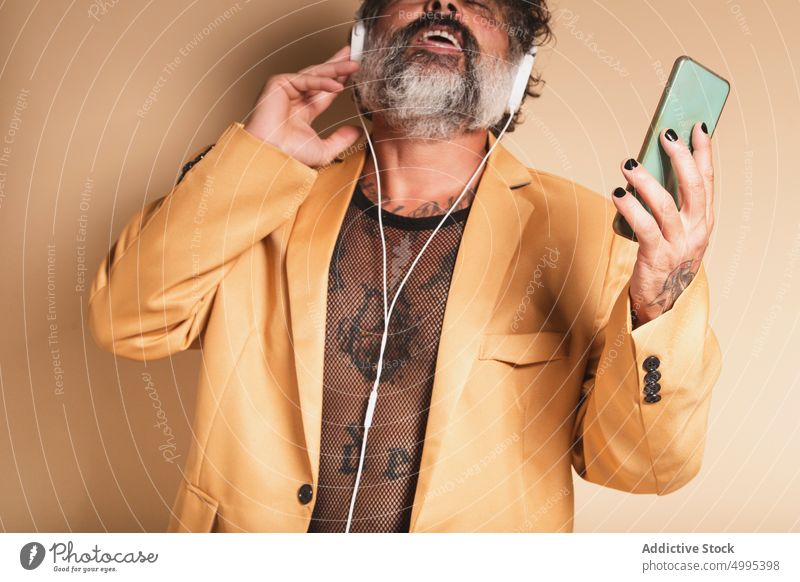Mature man listening to music in headphones sing eccentric studio enjoy song expressive male beard audio sound style voice gadget device smartphone mobile