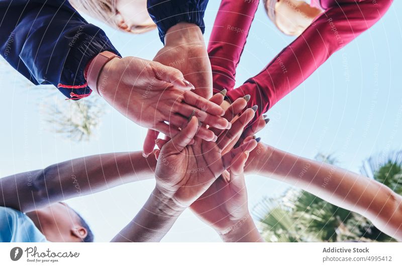 Crop unrecognizable multiethnic friends stacking hands in park women stack hands team join together athlete training hands together blue sky cloudless support