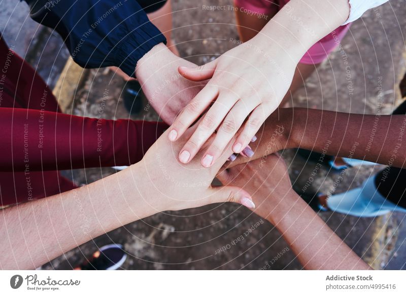Crop unrecognizable multiethnic friends stacking hands in park women stack hands team join together athlete training hands together support unity young