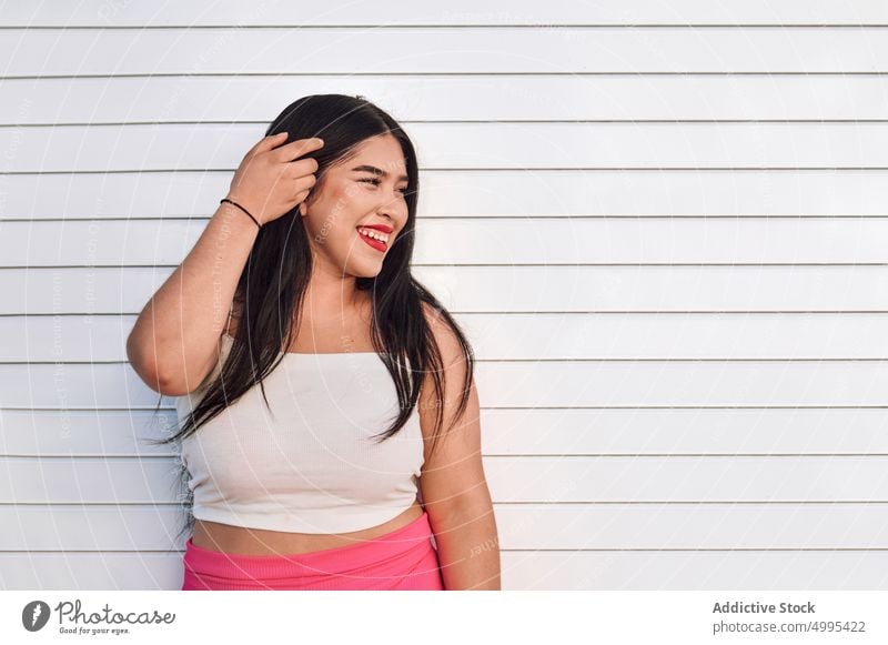 Stylish plus size woman standing on street smile style white wall urban appearance happy female ethnic young cheerful overweight plump chubby glad daytime