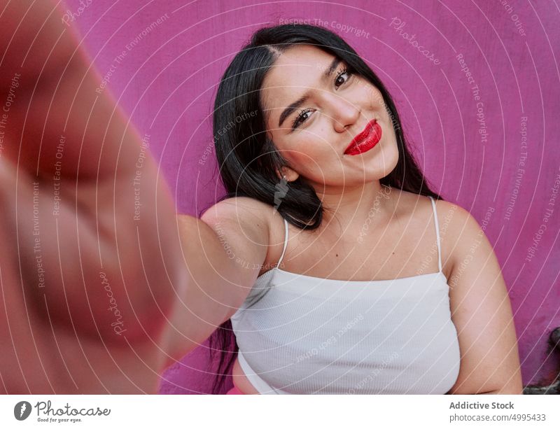 Young ethnic woman taking selfie smile wall happy street appearance plus size style modern female young black hair bright red lips optimist cheerful plump