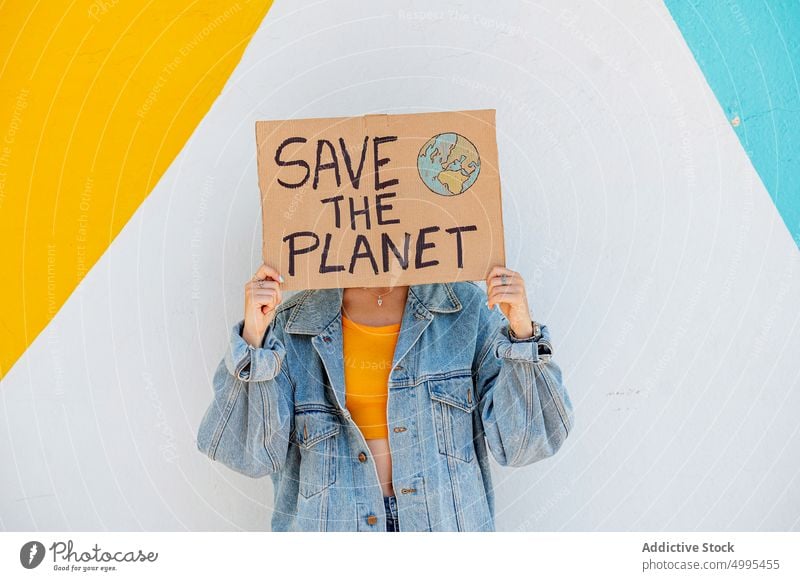 Anonymous female showing ecological poster woman environment ecology save the planet bright protest event young casual denim banner wall placard demonstrate