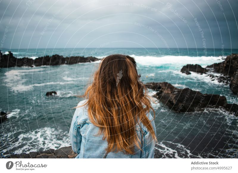 Anonymous woman admiring stormy sea admire wave cliff water tourist weekend coast la palma canary islands spain female long hair nature trip observe ocean