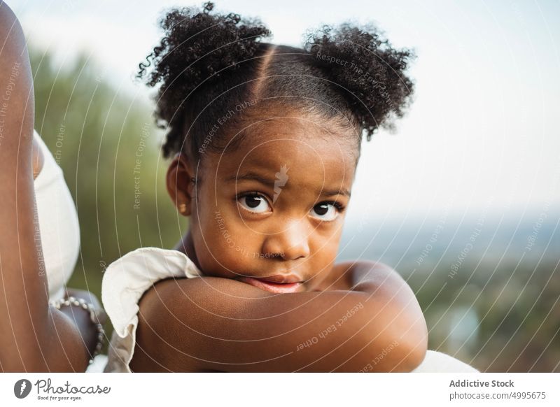 African American girl looking at camera near mom daughter mother countryside summer weekend together generation portrait cute child kid parent black