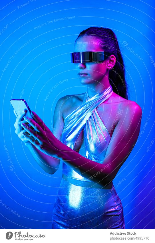 Serious futuristic woman on mobile phone in blue studio virtual reality smartphone style browsing experience social media confident vr cyberspace digital female