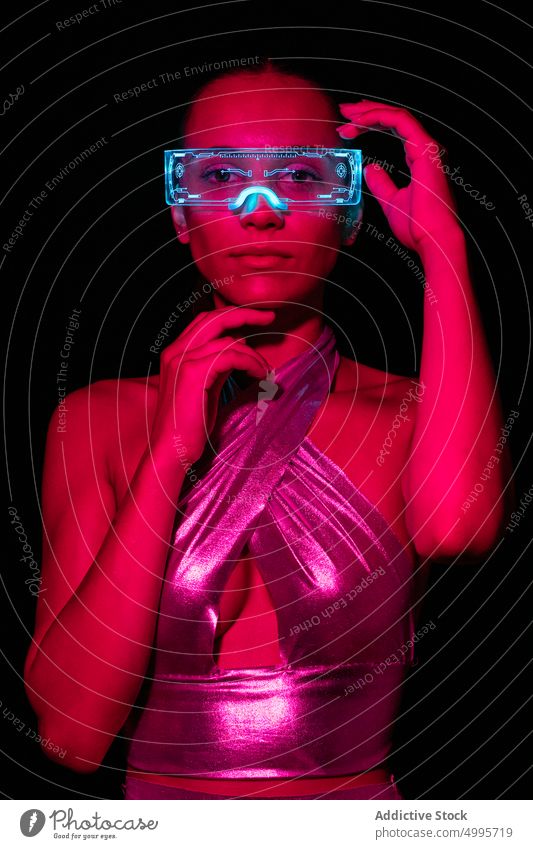 Young woman in transparent VR goggles exploring virtual reality against black background touch interact experience simulate vr innovation futuristic digital
