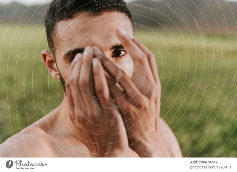 Calm Hispanic guy covering face in nature man cover face shirtless field serious hide calm personality tranquil confident peaceful individuality male young