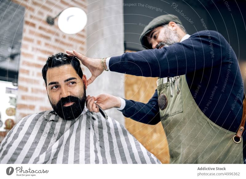 Crop barber cutting hair of client with razor straight blade haircut grooming barbershop mature men sharp professional customer salon work tool male service job