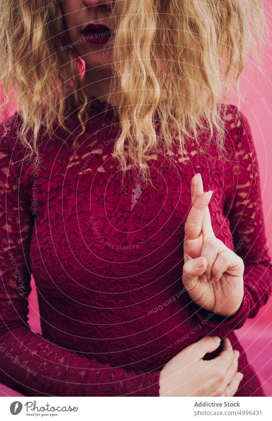 Woman with crossed fingers in studio woman fingers crossed gesture sign symbol model blond wavy hair show female demonstrate style lady hope wish hopeful