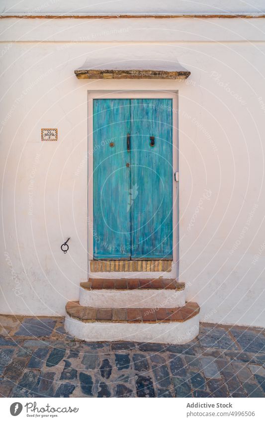 Blue wooden door in plastered old wall exterior shabby entrance facade aged paint stone house building weathered doorway turquoise entry town architecture