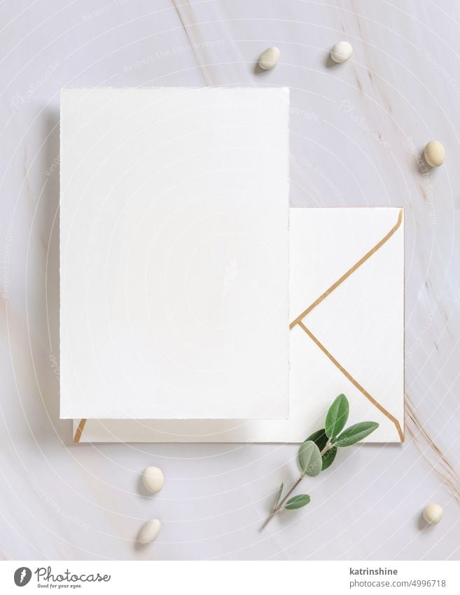 Vertical card on a marble table decorated with eucalyptus branches top view, Wedding mockup leaves green envelope stone pearl blank invitation romantic