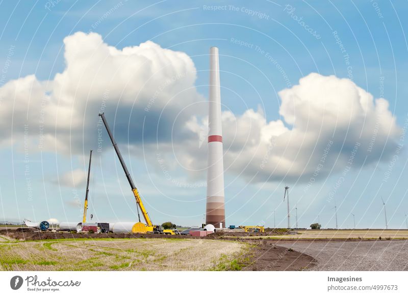 Construction and assembly of a wind turbine by crane. Farmland with construction work at Wörrstadt wind farm, Germany. Energy saving concept from wind turbine construction