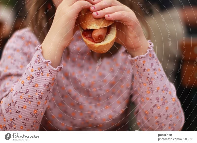 A child in flowered top bites into a hotdog. Fast food Wienerwurst roll Eating enjoyment Delicious Girl Food Nutrition Snack garments Pattern Floral Top part