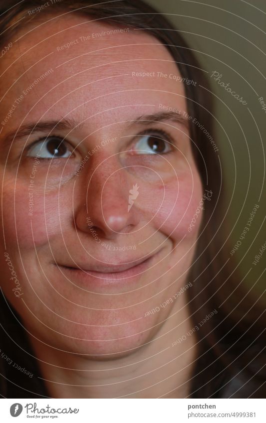 Woman with mischievous smile turns her eyes upwards portrait Face twist your eyes Amused Smiling Impish brown eyes Feminine Adults Long-haired Looking naturally