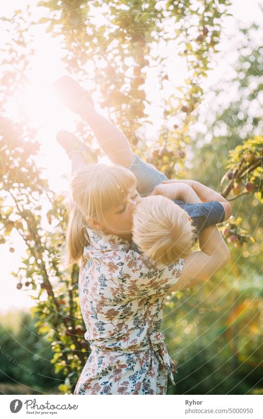 Young Woman Mother Hugging And Kissing Her Baby Son In Sunny Garden. Outdoor Summer Portrait baby beautiful blonde boy care caucasian child childhood delicate