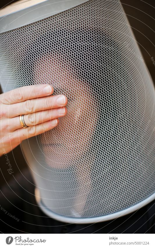 Woman with metal basket over her head holds her hand in front of her eyes Hand eyes closed Close-up Strange facial expression Grief insulation frustrated Face