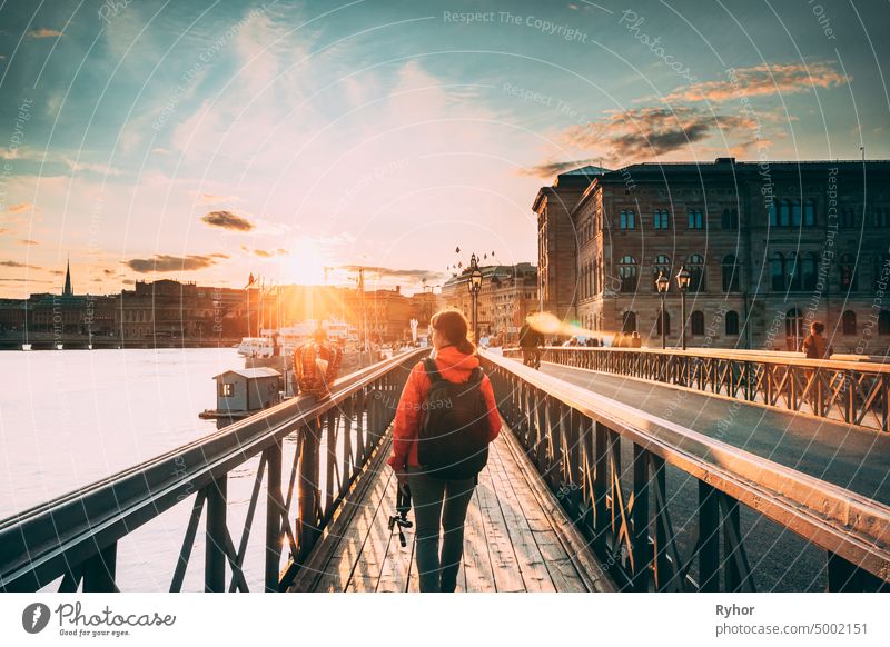 Stockholm, Sweden. Young Caucasian Woman Lady Tourist Traveler Walking On Famous Skeppsholmsbron - Skeppsholm Bridge. Popular Place, Landmark  And Destination In Stockholm, Sweden