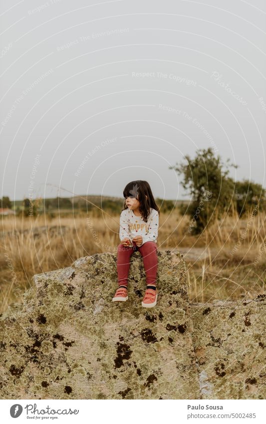Cute girl sitting on rock Child childhood Girl 3 - 8 years Rock Field Nature Childhood memory Lifestyle Leisure and hobbies Human being Exterior shot Authentic