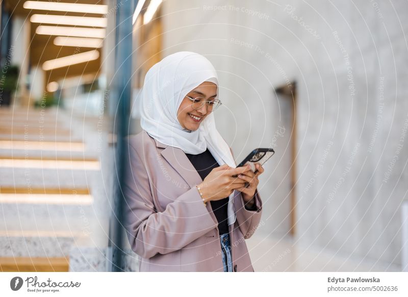 Young muslim woman using smartphone indoors Thai scarf hijab islam islamic university business office real people young adult student positive smiling cheerful
