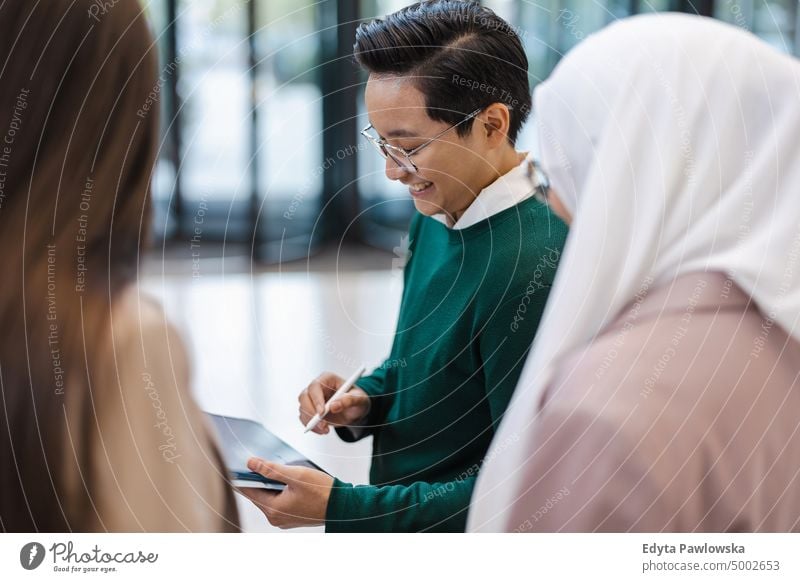 Young businessman showing something to his colleagues on tablet in office Multiracial Group team diversity teamwork muslim Multi-ethnic group real people young