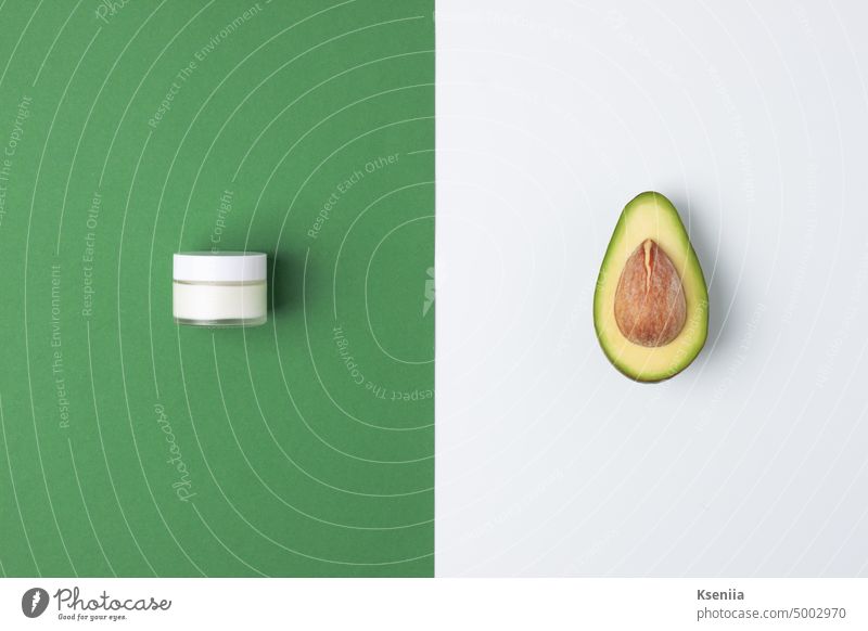 Minimal composition with jar of cosmetic cream and avocado on green and white background. Flat lay, copy space bathroom beauty body body care cleanser cosmetics
