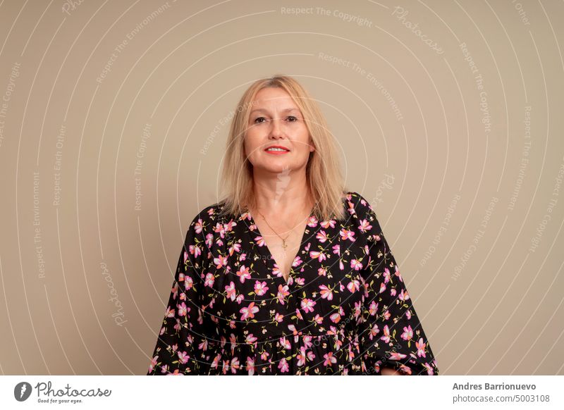 Cheerful smiling woman with blond hair, casually dressed, looking with satisfaction at camera, being happy. Studio shot of beautiful pretty woman isolated against studio wall on beige.
