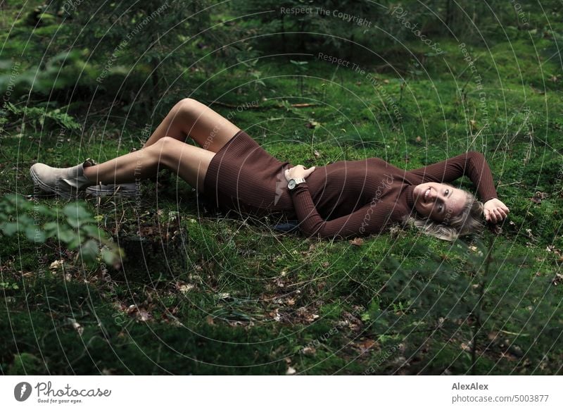 Young blonde woman lying on the moss in the forest and looking at the camera from the side Young woman Woman Blonde Feminine pretty fortunate
