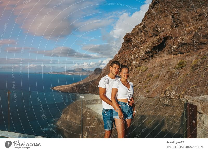Couple on their honeymoon on a viewpoint against volcanic cliffs couple love young caucasian 20s sunset kiss copy space rocks canary islands spain sea ocean
