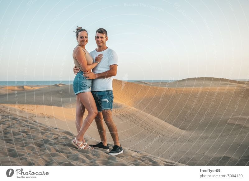 Young couple on their honeymoon visiting a sand dunes desert love walking maspalomas Gran Canaria copy space Canary islands Spain tourist travel hiking outdoors