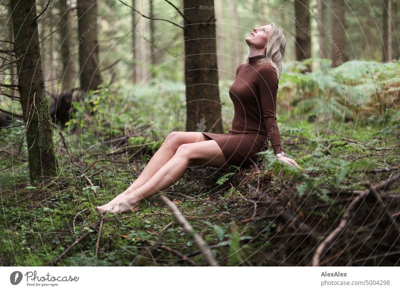 Young blonde woman sitting barefoot on fallen tree trunk in forest looking at sky Young woman Woman Blonde Feminine pretty fortunate Youth (Young adults)