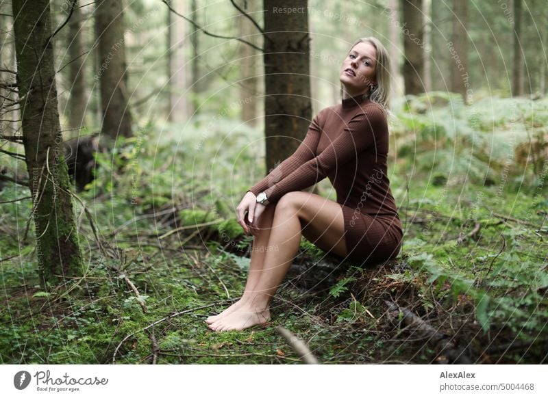 Young blonde woman sitting barefoot on fallen log in forest looking at camera Young woman Woman Blonde Feminine pretty fortunate Youth (Young adults) portrait